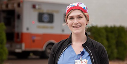 A smiling emergency responder with an ambulance in the background