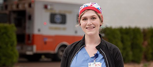 A smiling emergency responder with an ambulance in the background