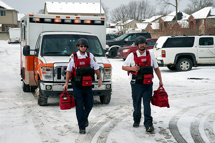 First responders in rescue gear leaving their ambulance with their equipment