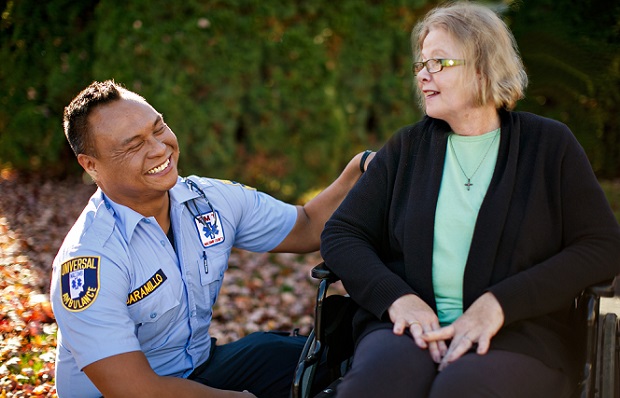 First responder smiling while talking to a woman sitting in a wheelchair